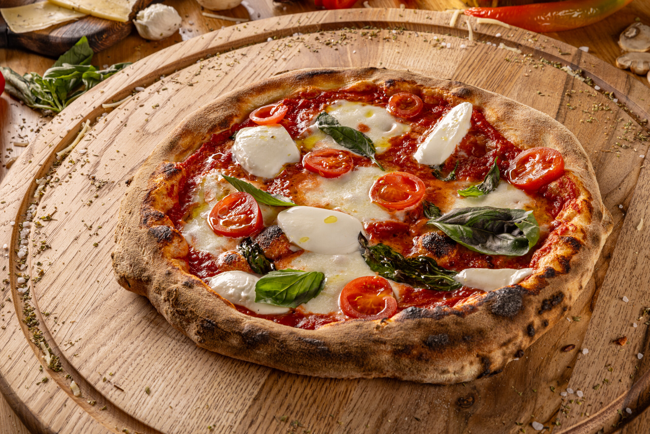 Appetizing margherita pizza with fresh basil, tomato, and mozzarella on a rustic wooden table