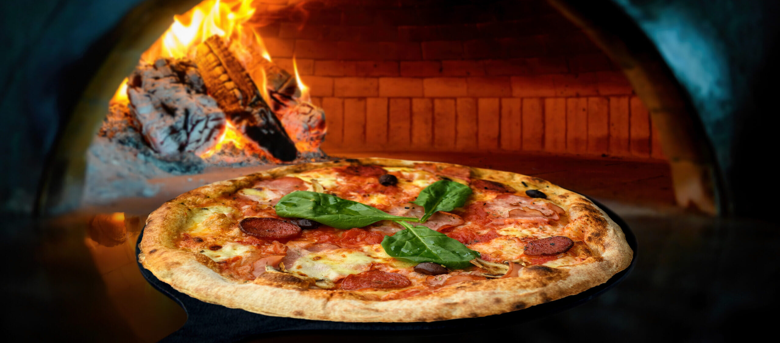 Close Delicious Italian pizza in a shovel putting in wood burning oven